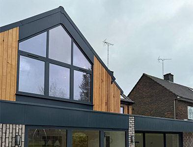 Apex gable glazing in slim anthracite frames on a timber-clad extension