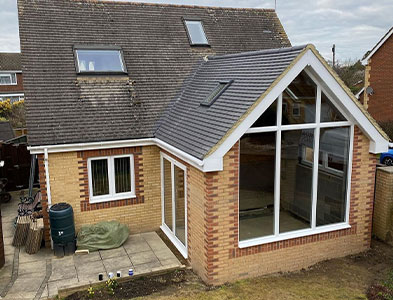 White-framed apex glazing on a brick extension with grey tiled pitched roof
