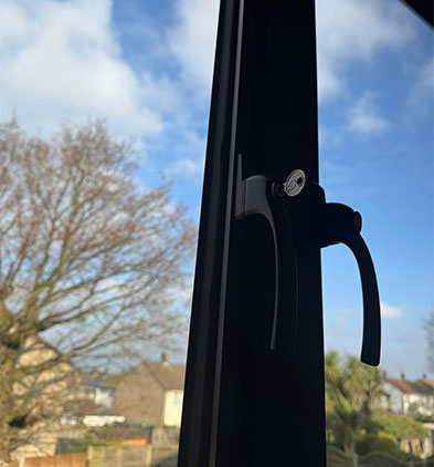 Close-up of a black lockable handle on a slim anthracite frame with keyhole