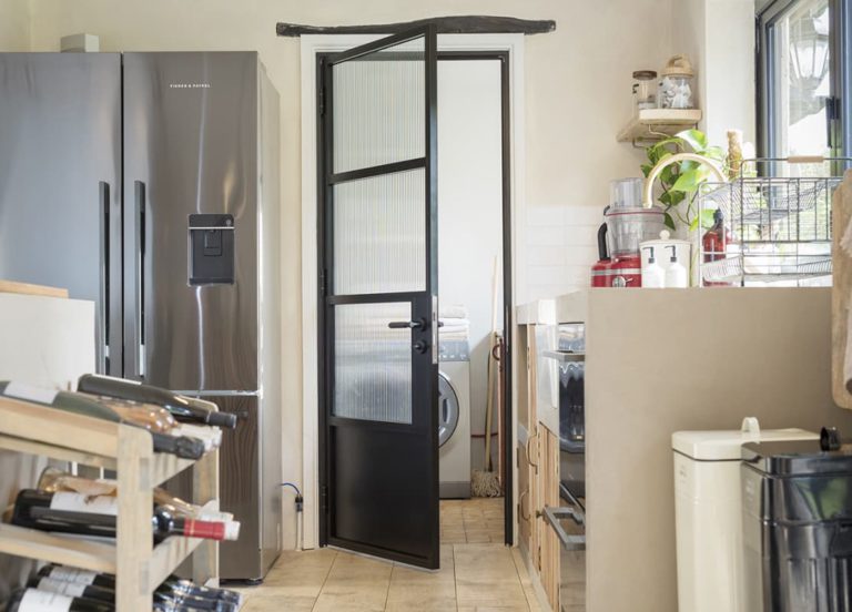 Black aluminium internal door with reeded glass panels between a kitchen and utility room