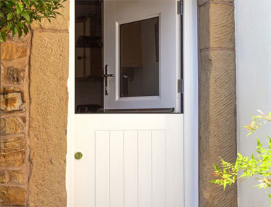 White stable-style entrance with the top half open in a stone cottage surround