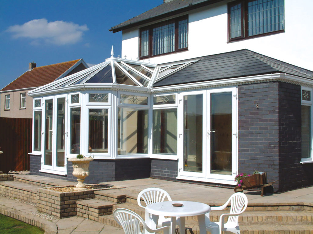 White uPVC garden room with glazed lantern roof and French entrances onto a patio