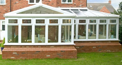 Large white glazed extension on a red brick dwarf wall spanning the rear of a home
