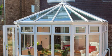 White Victorian-style glazed room with a pitched glass roof and finial detail