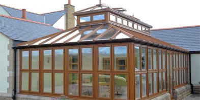 Oak-effect glazed extension with a tiered roof lantern on a stone-built home