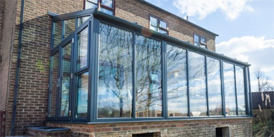 Anthracite lean-to glazed room with full-height panes against a brick house