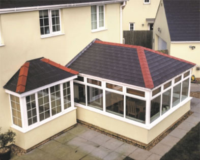 Cream rendered garden room with a solid grey tiled roof and white glazed frames