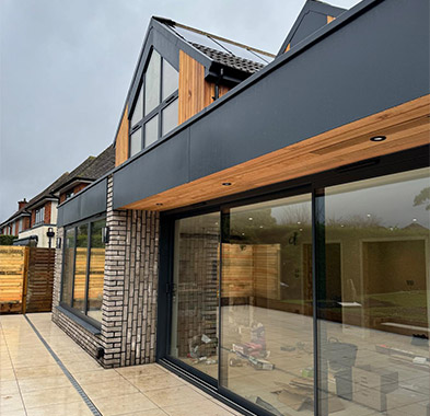 Modern extension with full-height anthracite panes and apex gable panes above timber cladding